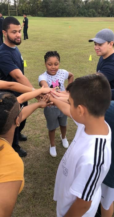 Kids and coaches putting their hands in together